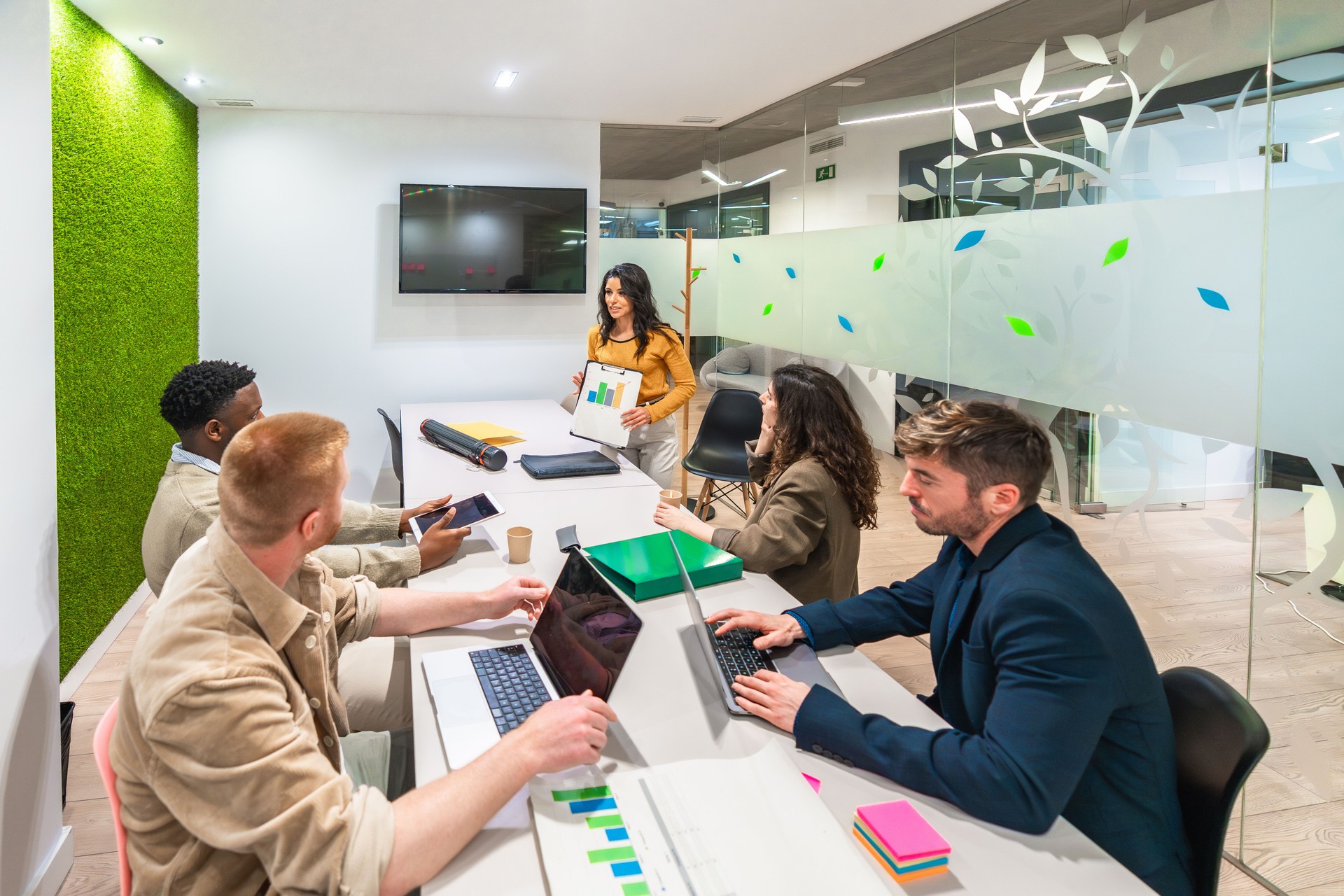 Marketing team analyzing charts on laptops and tablets in modern office