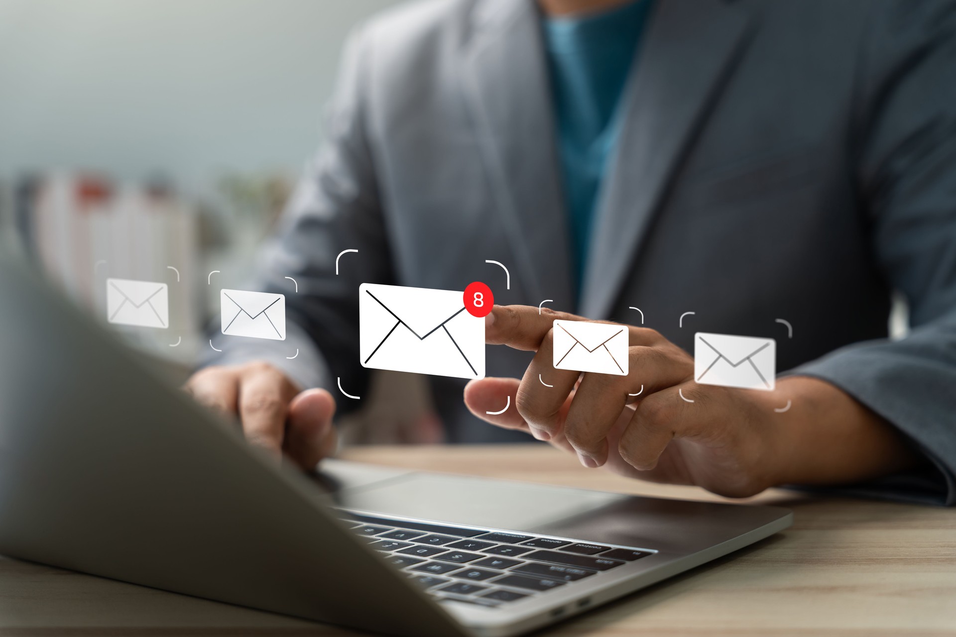 Businessman checking email notifications on laptop with digital mail icons. Concept of communication, inbox alert, email marketing, remote work, and modern business connectivity.